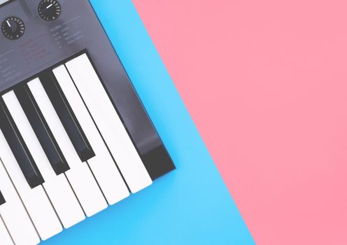 Music keyboard synthesizer instrument on blue pink copy space
