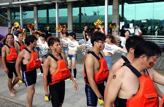 KAOHSIUNG, TAIWAN -- MAY 25, 2014: Pretty cheerleaders spur on a team of athletes as they get ready to take part in the 2014 Dragon Boat Races on the Lotus Lake.