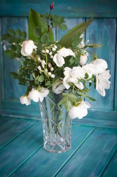A wedding bouquet of lilies of the valley and white roses. Teal wooden background