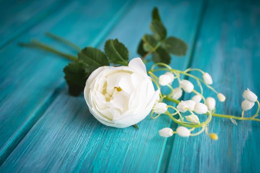 Romantic white bouquet with tender rose tree and lilly of the valley flowers, teal wooden background.
