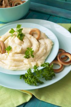 Golden mashed potatoes with parsley, decorated with bublik. Vertical image