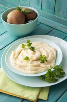 Mashed potatoes in bowl on blue teal wooden table, vertical image