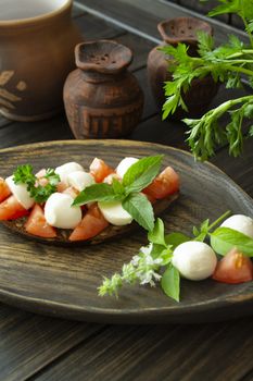 Bruschetta with red tomatoes, mozzarella cheese and basil on a old rustic dark table. Vertical image