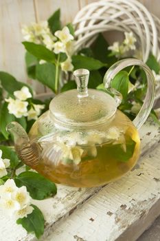 green tea with jasmine in glass teapot on wooden shabby table, vertical image