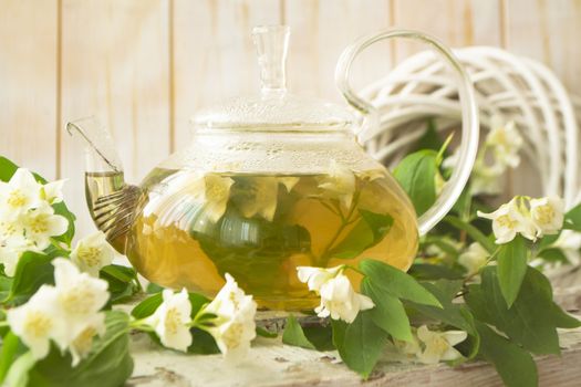 glass teapot with hot tea and jasmine flowers. Closeup