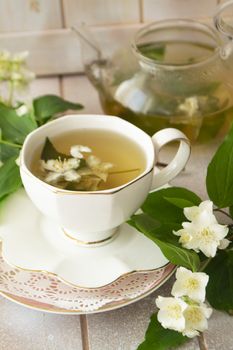 Jasmine tea with jasmine flowers on white wooden table background. Cup of hot green tea with jasmine flavor, fresh jasmine flowers. Concept of freshly drink. Vertial image
