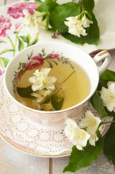 Vintage cup of hot green tea with jasmine flavor and fresh jasmine flowers. Vertical image