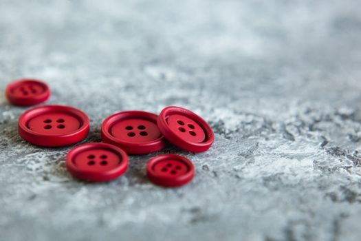 Pile of red matte buttons on concrete background, macro bokeh. beautiful needlework