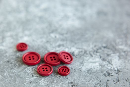 Pile of red matte buttons on concrete background, macro bokeh. beautiful needlework