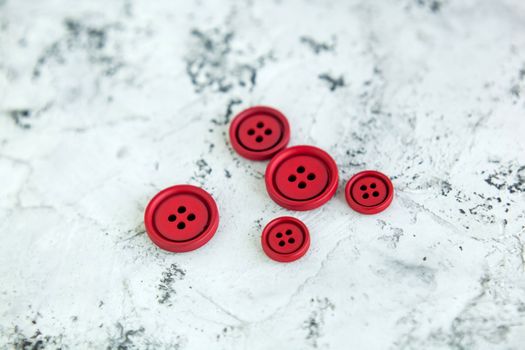 Pile of red matte buttons on concrete background, macro bokeh. beautiful needlework