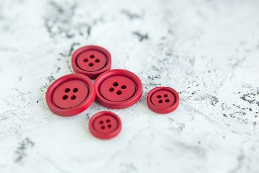 Pile of red matte buttons on concrete background, macro bokeh. beautiful needlework