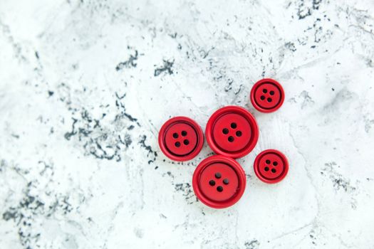 Pile of red matte buttons on concrete background, macro bokeh. beautiful needlework