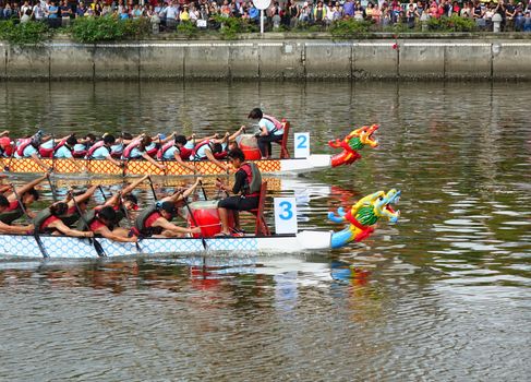 KAOHSIUNG, TAIWAN -- JUNE 9, 2016: Two unidentified teams compete in boat races on the Love River during Dragon Boat Festival.