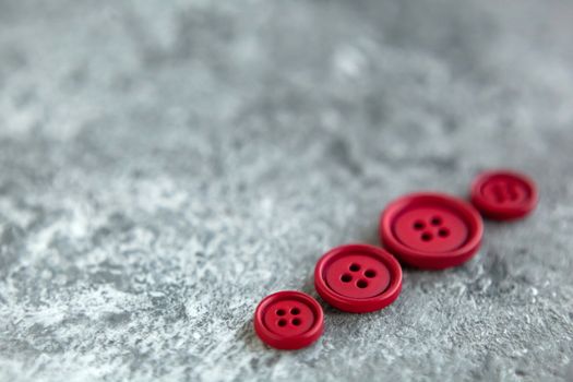 Pile of red matte buttons on concrete background, macro bokeh. beautiful needlework