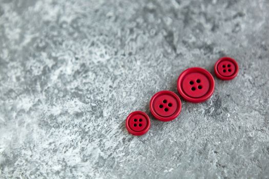 Pile of red matte buttons on concrete background, macro bokeh. beautiful needlework