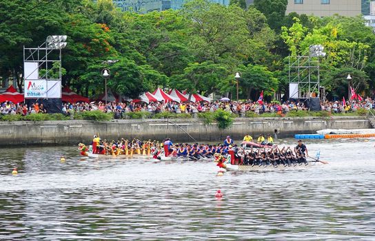 KAOHSIUNG, TAIWAN -- JUNE 9, 2016: Three unidentified teams compete in boat races on the Love River during Dragon Boat Festival.
