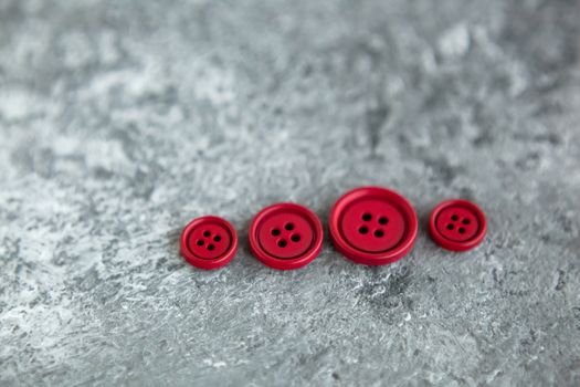 Pile of red matte buttons on concrete background, macro bokeh. beautiful needlework