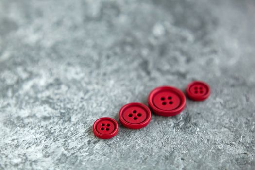 Pile of red matte buttons on concrete background, macro bokeh. beautiful needlework