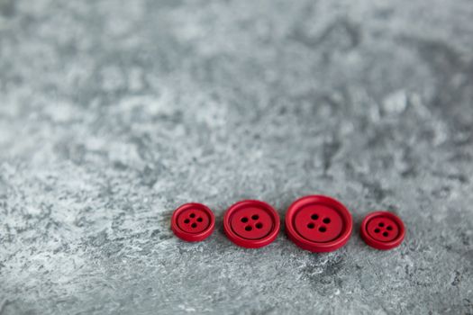 Pile of red matte buttons on concrete background, macro bokeh. beautiful needlework