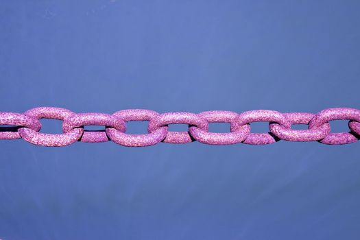 Old rusty colored chain on blue background - toned image