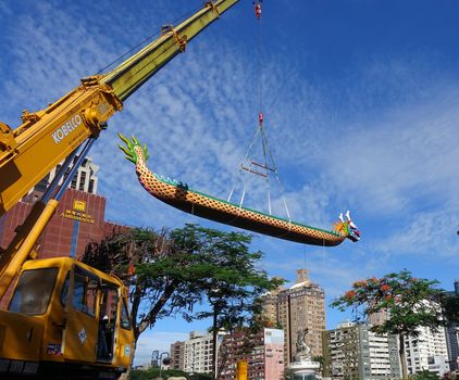 KAOHSIUNG, TAIWAN -- MAY 27, 2016: A crane lowers a dragon boat into the Love River in preparation for the upcoming Dragon Boat Festival.