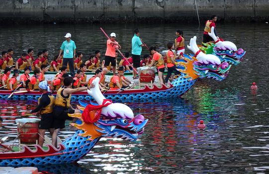 KAOHSIUNG, TAIWAN -- MAY 30, 2017: Three unidentified teams compete in the Dragon Boat Races on the Love River in Taiwan in the evening.