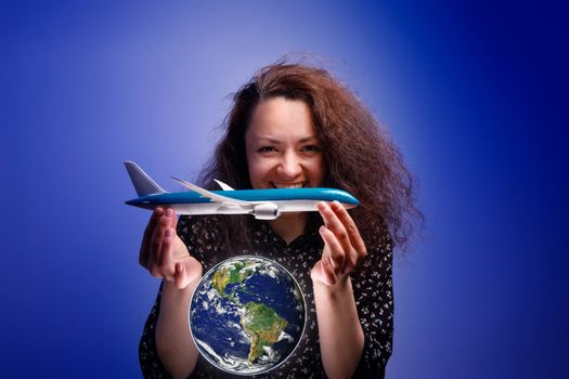 Girl with an airplane model in her arms over an earth globe. Concept of Airline help