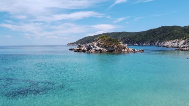 Aerial top view of Sithonia Chalkidiki peninsula above rocky coastal with green plantation and crystal-clear waters.
