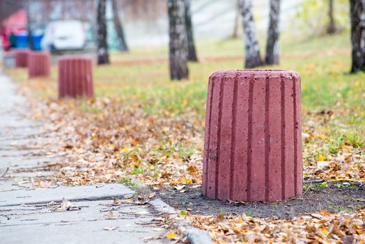New red cement trash bin in the park in autumn