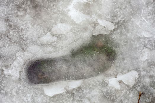 Footprint in the cold snow, under the ice, in winter