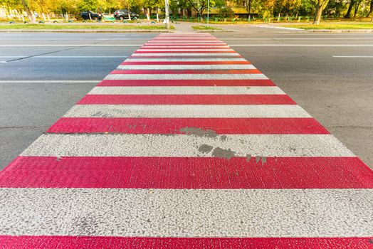 A red and white pedestrian crossing on blue black asphalt in the town of Kiev, Ukraine