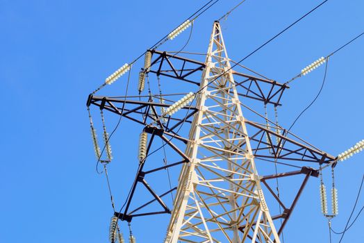 Electricity pylon against blue sky: high voltage electric cables seen from below . Room for text