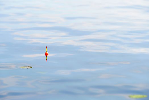 A yellow and orange fishing float in blue water