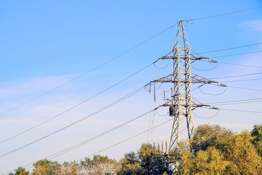 Electricity pylon against blue sky: high voltage electric cables seen from below . Room for text