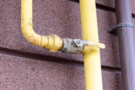 A yellow gas tube, with a tap, outside of a house to canalize the soft energy at home.