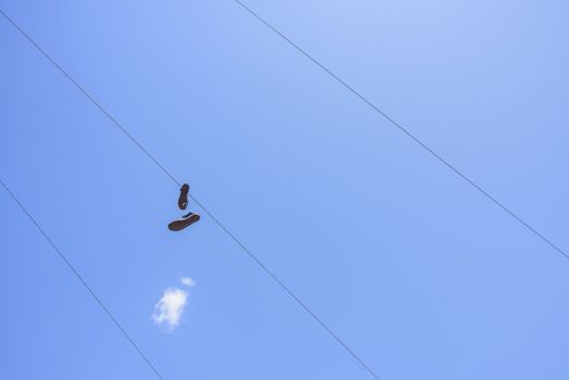 Shoes attached to an electric wire with a blue sky background