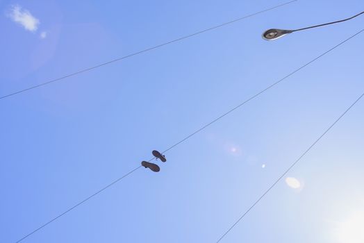 Shoes attached to an electric wire with a blue sky background