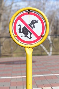 A sign in a park for no poop with the icon of a dog pooping.