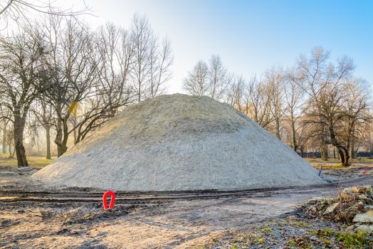 A huge sand pile during construction in the park at sunrise