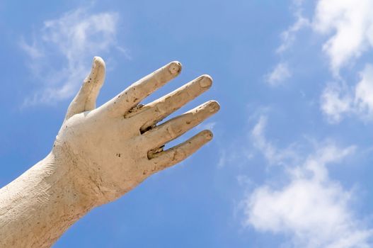 A statue hand showing the white clouds in the blue sky, as idea of freedom