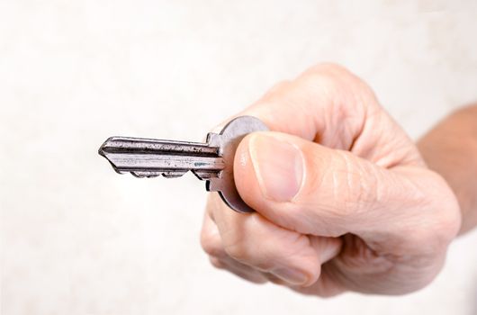 A man's hand is holding a key, opening or closing a door, on light background