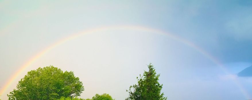 rainbow caused by reflection, refraction and dispersion of sun light in rain water droplets, resulting in spectrum of light in the sky in the form of a multicoloured circular arc