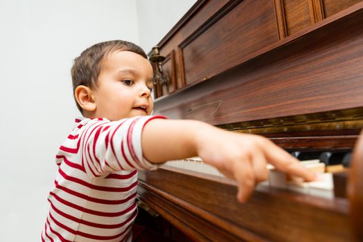 Litlle boy playing the piano, toddler learning music at home