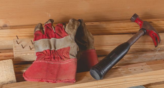 old rusty hammer and construction gloves laid on wooden board in studio