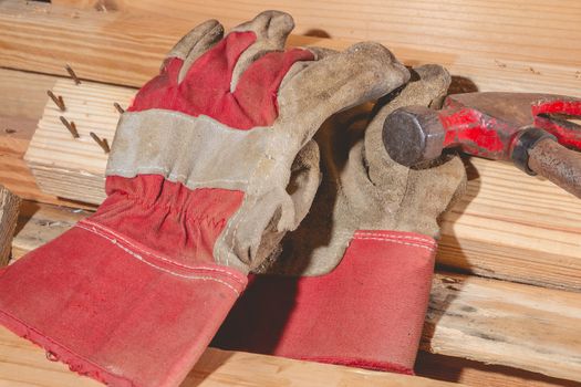 old rusty hammer and construction gloves laid on wooden board in studio