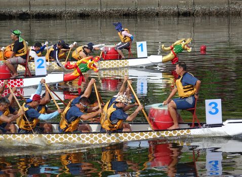 KAOHSIUNG, TAIWAN -- JUNE 18, 2015: Three unidentified teams compete in the 2015 Dragon Boat Races on the Love River in Kaohsiung City.