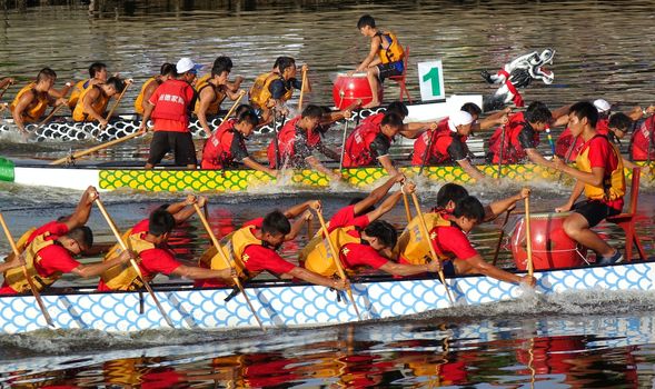 KAOHSIUNG, TAIWAN -- JUNE 18, 2015: Three unidentified teams compete in the 2015 Dragon Boat Races on the Love River in Kaohsiung City.