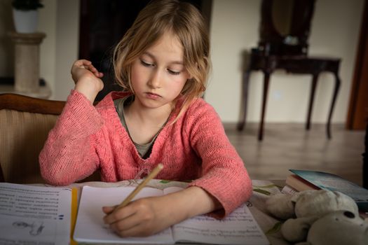 blond lefthanded girl writting homeworks during corona virus lockdown restrictions