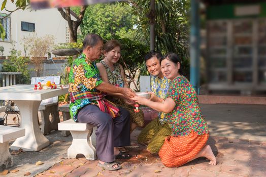 Asian young bathe with respect to parents by water have a jasmine and rose flower and aromatherapy in water in water bowl in Songkran Festival