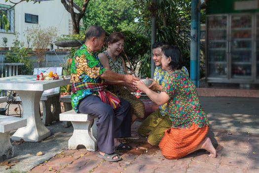 Asian young bathe with respect to parents by water have a jasmine and rose flower and aromatherapy in water in water bowl in Songkran Festival